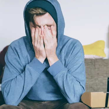 A stressed person holding his hands to his face